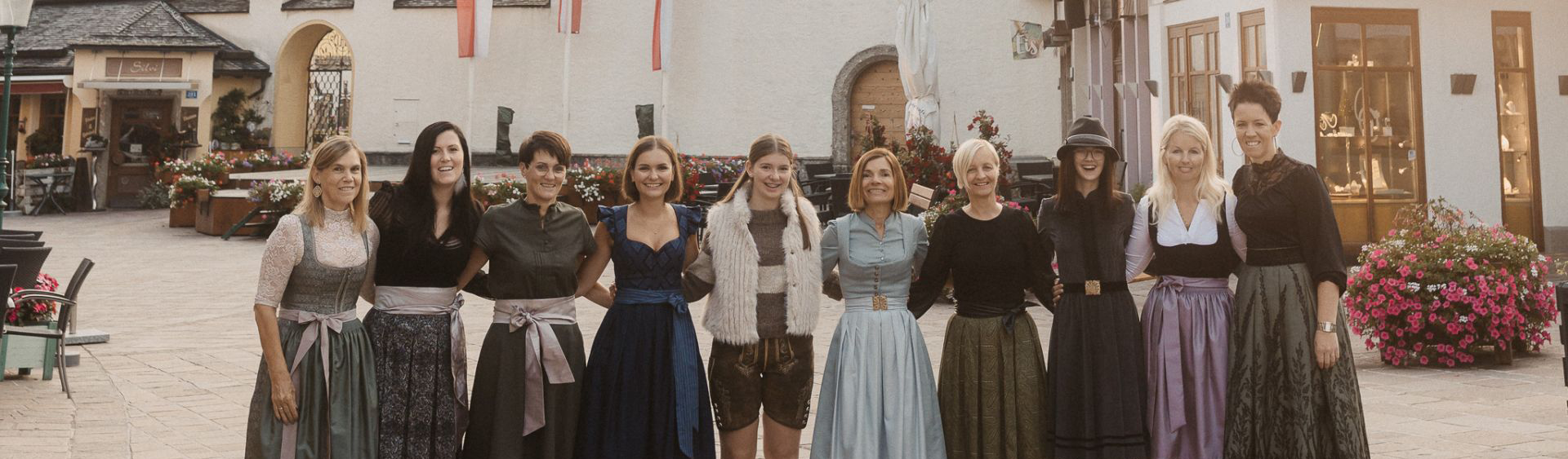 Gruppenfoto von Mitarbeiterinnen Moden Quehenberger in traditioneller Trachtenmode vor einem Geschäft im historischen Ortszentrum.